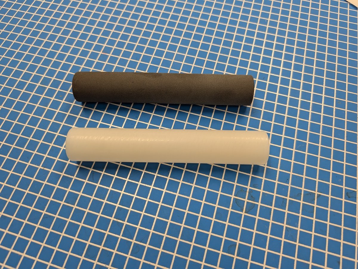 作業台に並ぶ黒い3Dプリント製スプリングリテーナーと白い比較部品